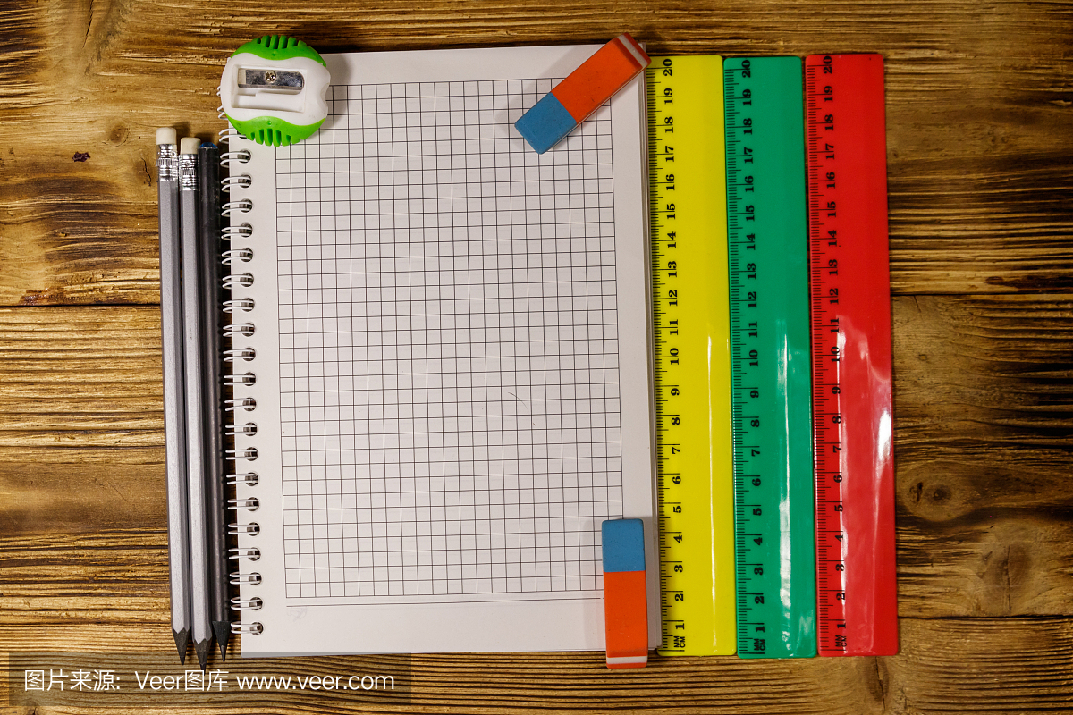 整套學校文具用品。木桌上的空白記事本、尺子、鉛筆、橡皮和卷筆刀。俯視圖